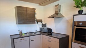 Une cuisine compacte équipée d’un four à micro-ondes, d’un grille-pain et d’un four encastré.
