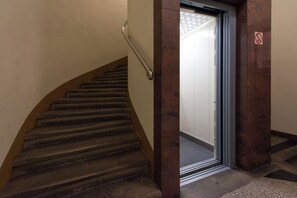 A staircase with a handrail, a door with a no-smoking sign, and a patterned floor.