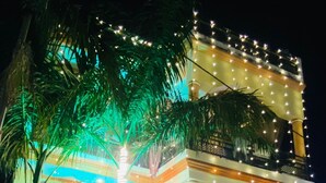 A multi-story building with a gated entrance, illuminated by string lights. - Rudra Homestay (Varanasi)