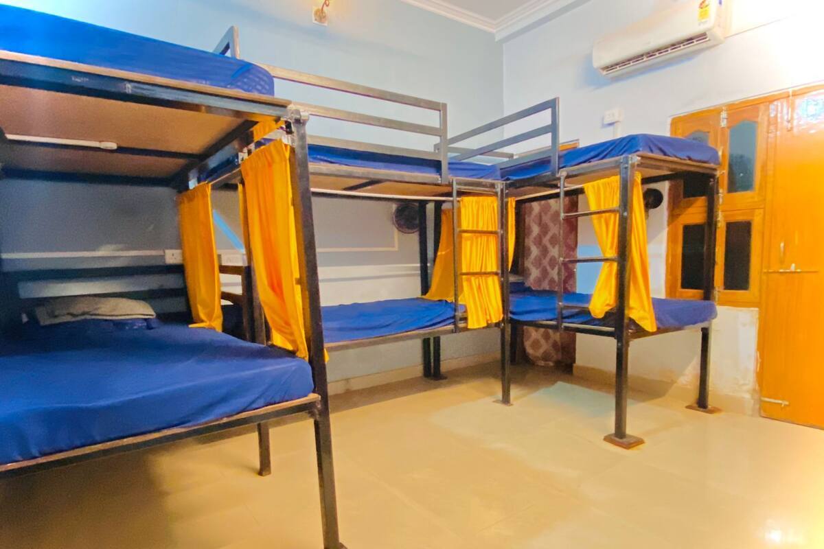Una habitació amb lliteres, cadascuna amb matalàs blau i cortines grogues.