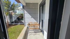 A modern outdoor patio with a wooden bench and a glass door leading to a garden. - Professionally Maintained Spacious New Suites 2-1 (Antalya)