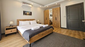A modern bedroom with a wooden bed, a nightstand, a wall-mounted air conditioner, and a door with a dark frame. - Professionally Maintained Spacious New Suites 2-1 (Antalya)