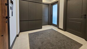 A hallway with dark-toned doors, a grey carpet, and recessed ceiling lighting. - Professionally Maintained Spacious New Suites 2-1 (Antalya)