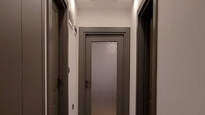 A hallway with a tiled floor, recessed ceiling lights, and doors on both sides. - Professionally Maintained Spacious New Suites 2-4 (Antalya)