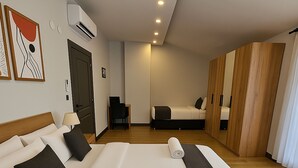 A hotel room with a large bed, a desk, a chair, a wardrobe, and an air conditioning unit. - Professionally Maintained Spacious New Suites 2-4 (Antalya)