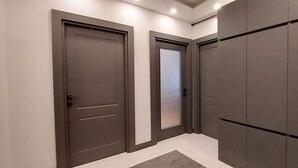 Un pasillo con dos puertas oscuras, piso de color claro y alfombra gris.