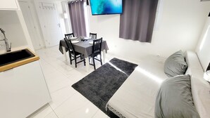 A modern hotel room with a dining area, a flat-screen TV, and a bed with pillows. - Magnificent maisonnette with private pool, 25min from beaches, 5 minutes from Montpellier (Juvignac)