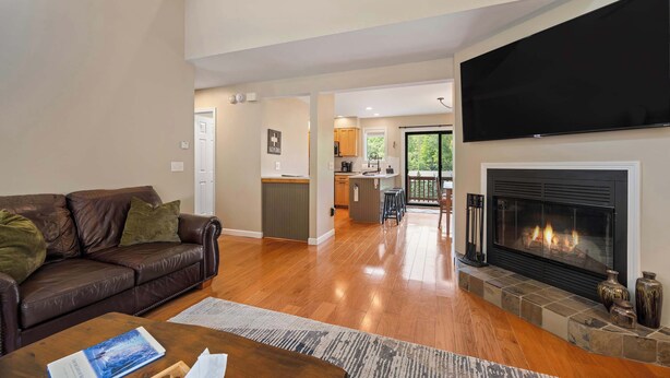 A spacious living room with a leather sofa, a fireplace, and a flat-screen TV. - 3 Bedroom Townhouse Across from Holimont (Ellicottville)