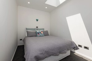 A bedroom with a bed, a heart-shaped decoration on the wall, and a skylight.
