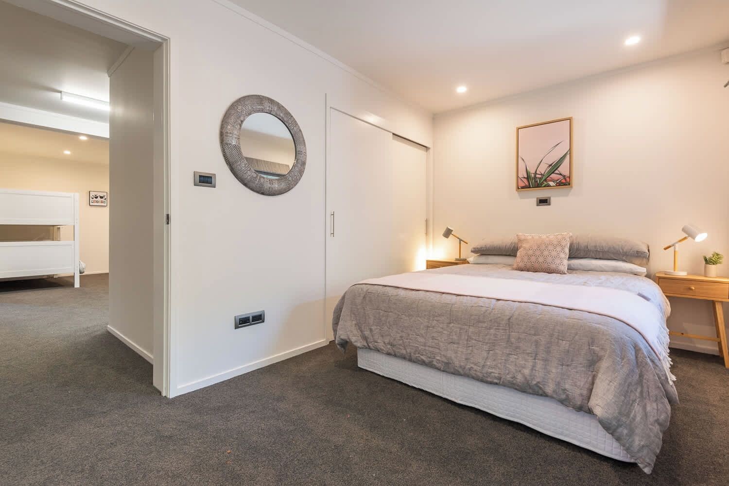 A bedroom with a bed, bedside tables, a mirror, and a door.