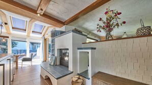 A modern kitchen with skylights, a fireplace, and a wooden stool. - Apartments Enzian (Rauris)