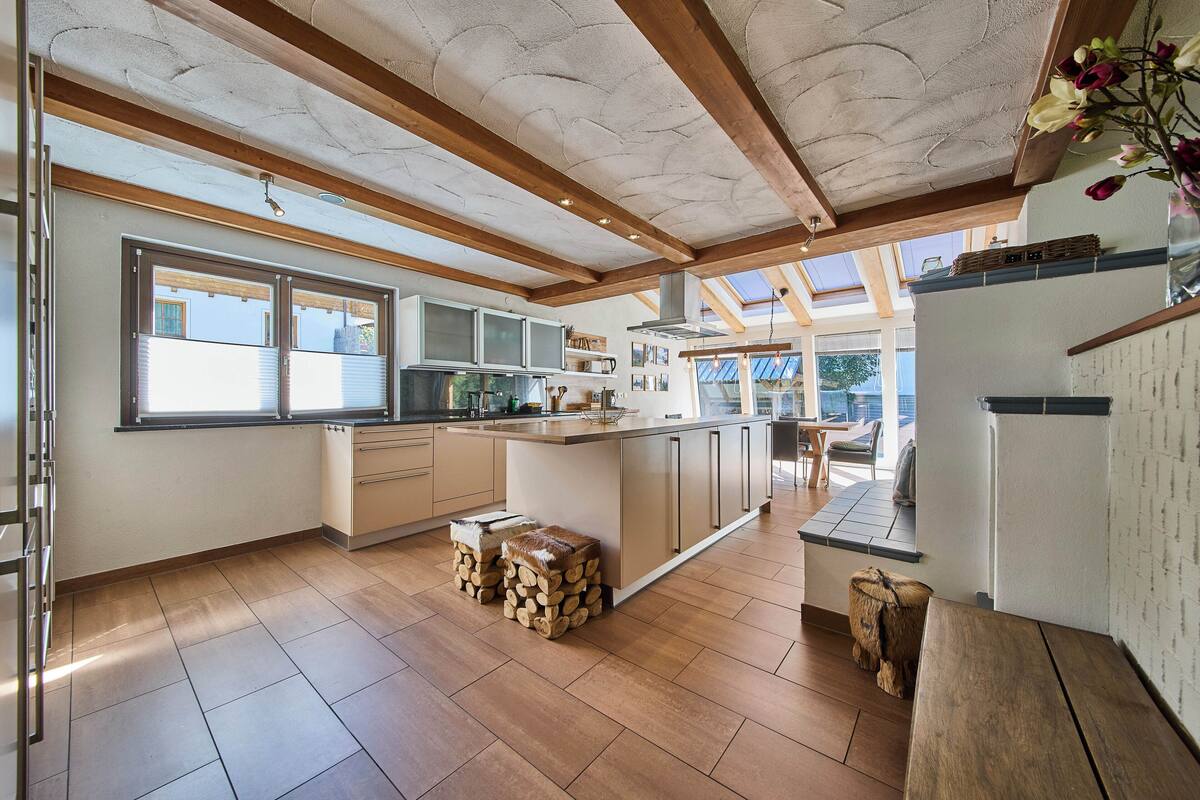 A spacious kitchen with wooden beams, a large island, and a view of the outdoors.