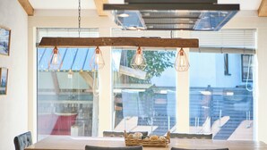 A dining area with a wooden table, black upholstered chairs, and a woven basket on the table. - Apartments Enzian (Rauris)