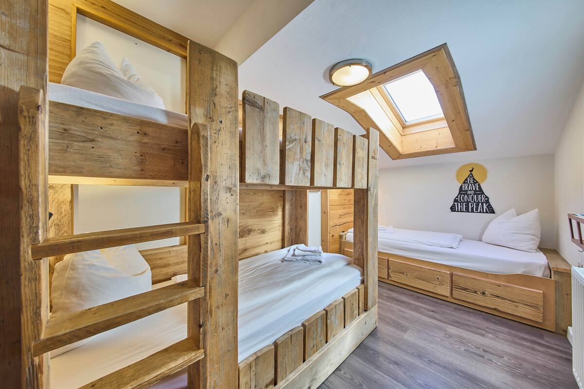 A loft bedroom with a bunk bed, a daybed, and a skylight.