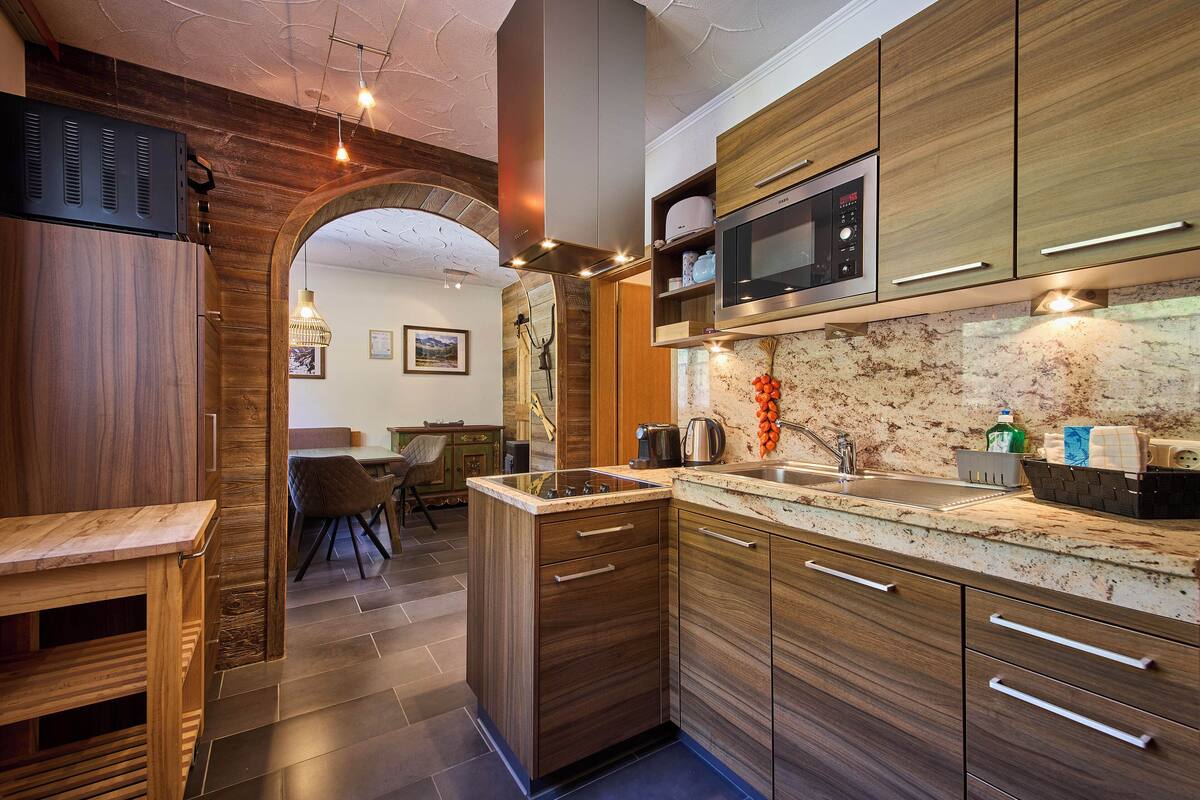 A modern kitchen with wooden cabinets, a built-in microwave, and a large island with a sink.