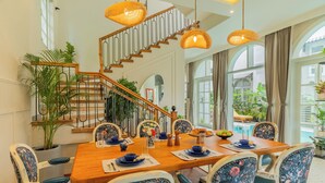 Un coin repas avec une table en bois, des chaises à motifs floraux et un escalier doté d’une rampe.