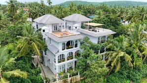Un immeuble à plusieurs étages, doté d’un toit plat, entouré d’une végétation tropicale luxuriante.
