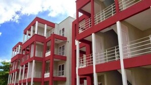 A multi-story building with balconies and a parking lot in front.
