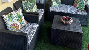 A cozy outdoor seating area with wicker furniture and decorative lighting.