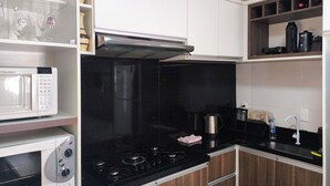 A compact kitchen with a microwave, stove, and black countertop.