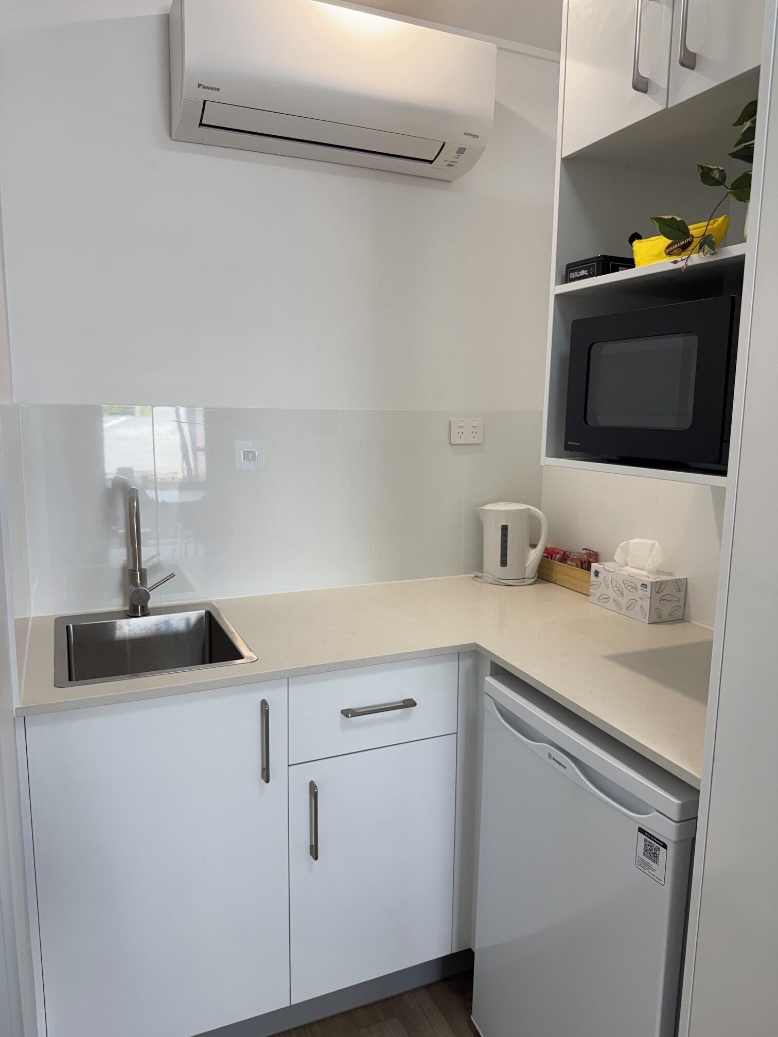 A compact kitchen with a built-in microwave, a sink, and a dishwasher.