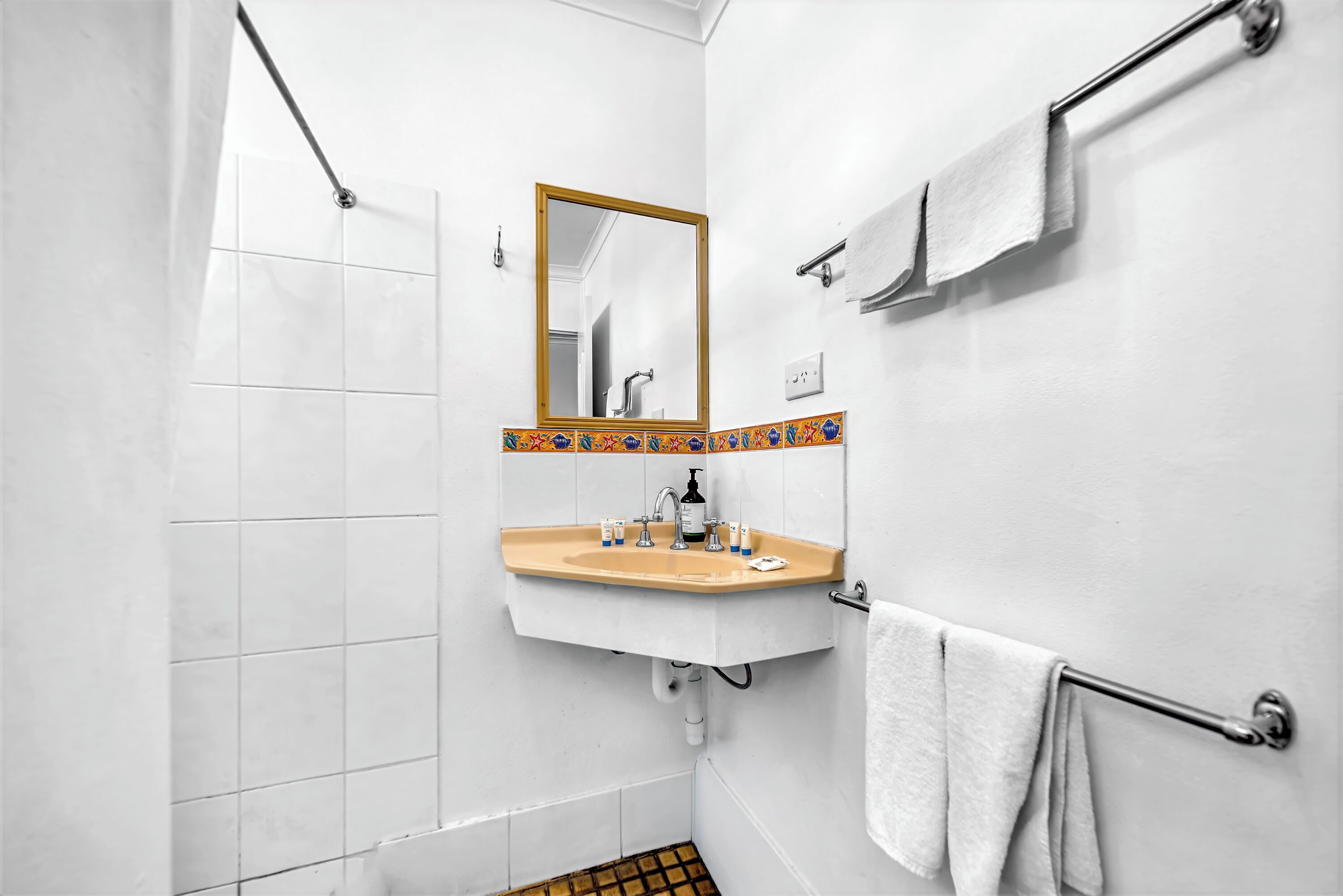 A bathroom with a white sink, mirror, and towel rack.