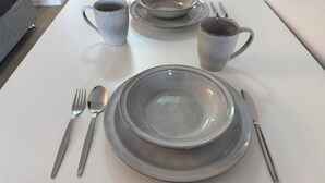 A dining table set with plates, bowls, a mug, and cutlery. - Pearly Shell Motel (Bowen)