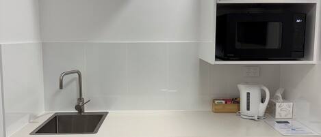 Una cocina compacta con microondas integrado, un fregadero y lavavajillas.