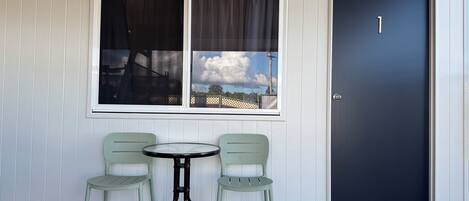 A room with a window, a door marked with the number 1, and two chairs around a small table.
