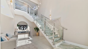 A spacious living area with a modern staircase, a sofa set, and a potted plant. - Ponton 34-g (Oranjestad)