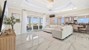 A spacious living area with a large sofa, a dining table, and a kitchen in the background. - Ponton 34-g (Oranjestad)