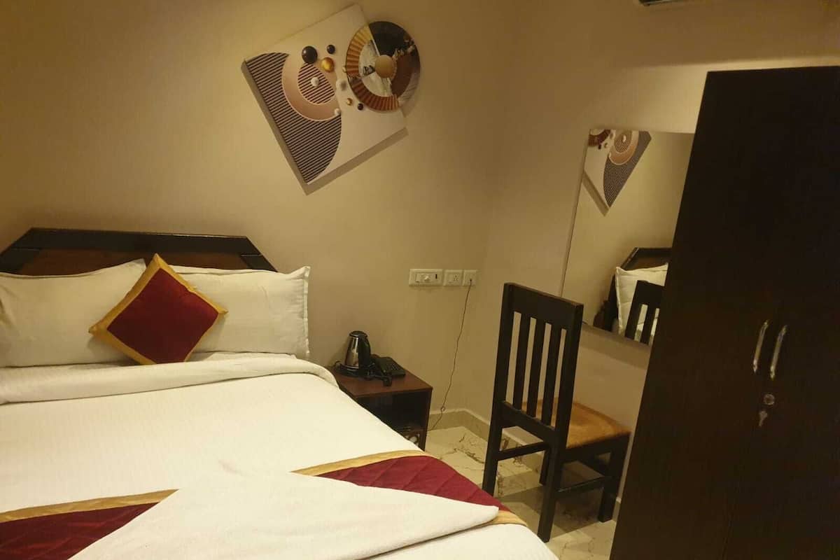 Una habitación de hotel con cama, una silla, un escritorio y un armario.
