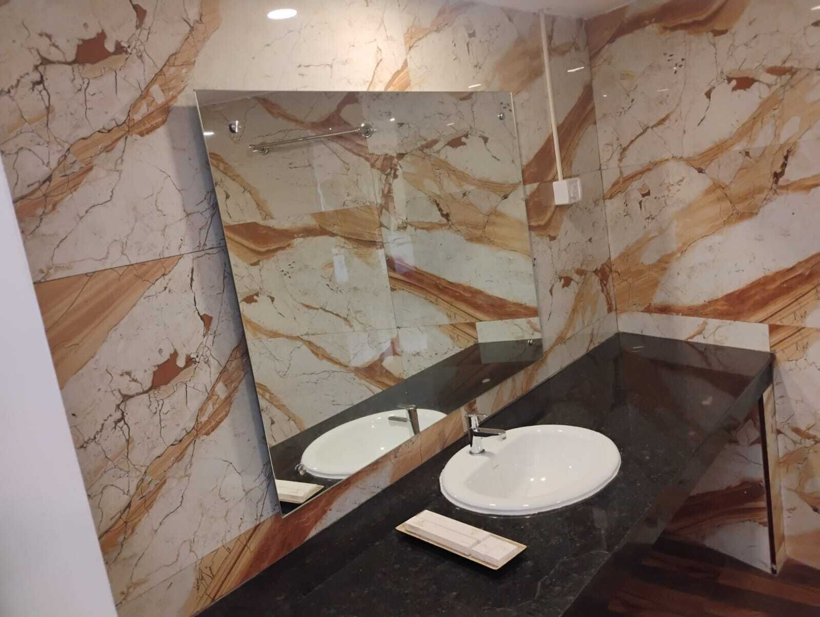 Ein modernes Badezimmer mit Marmorwand, schwarzem Waschtisch und weißem Waschbecken.