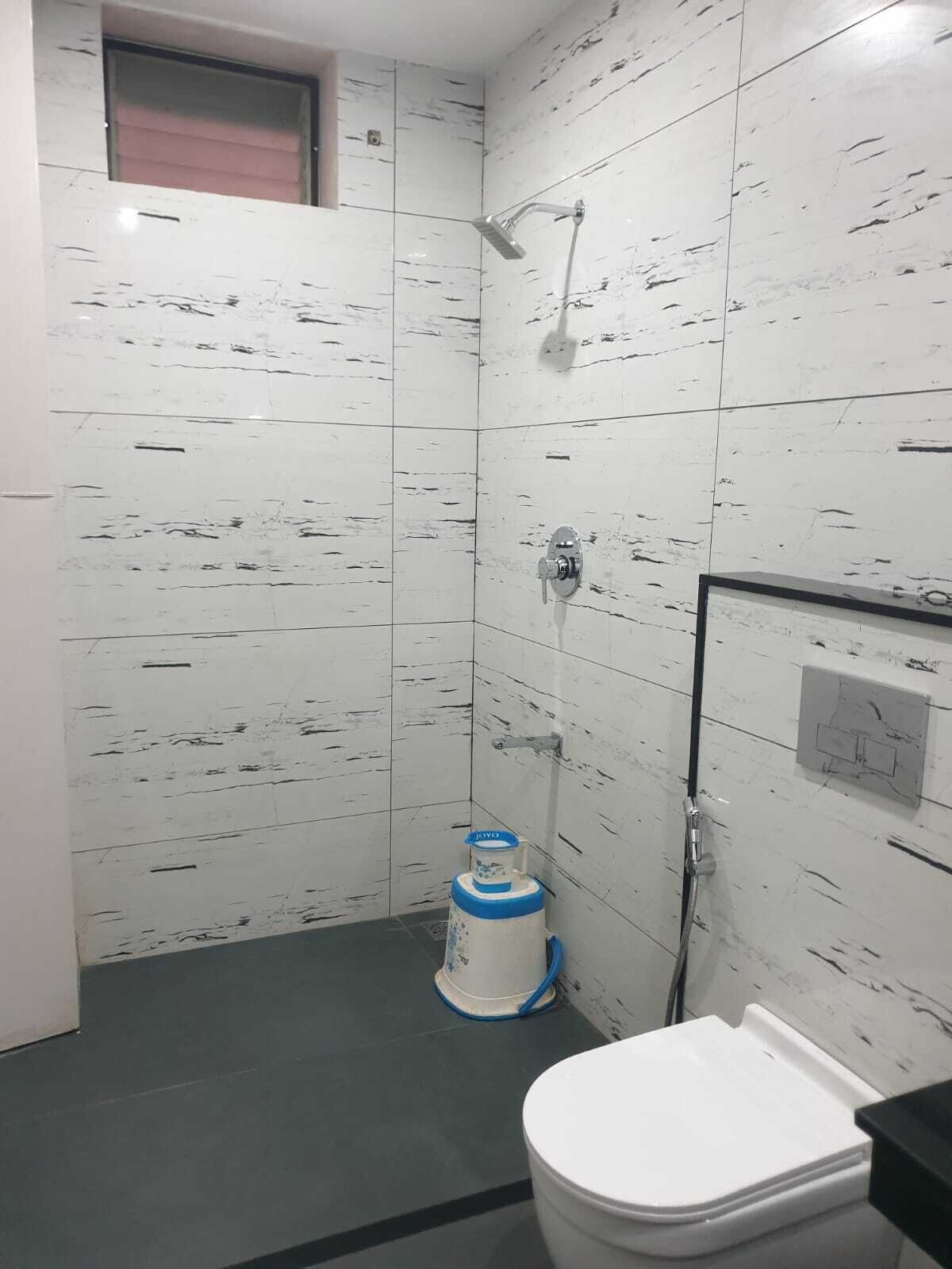 Un baño con paredes de azulejos blancos, una ducha, un inodoro y un calentador de agua azul y blanco.