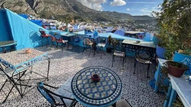 Une terrasse extérieure, dotée de tables et de chaises, qui offre une vue sur un paysage montagneux.