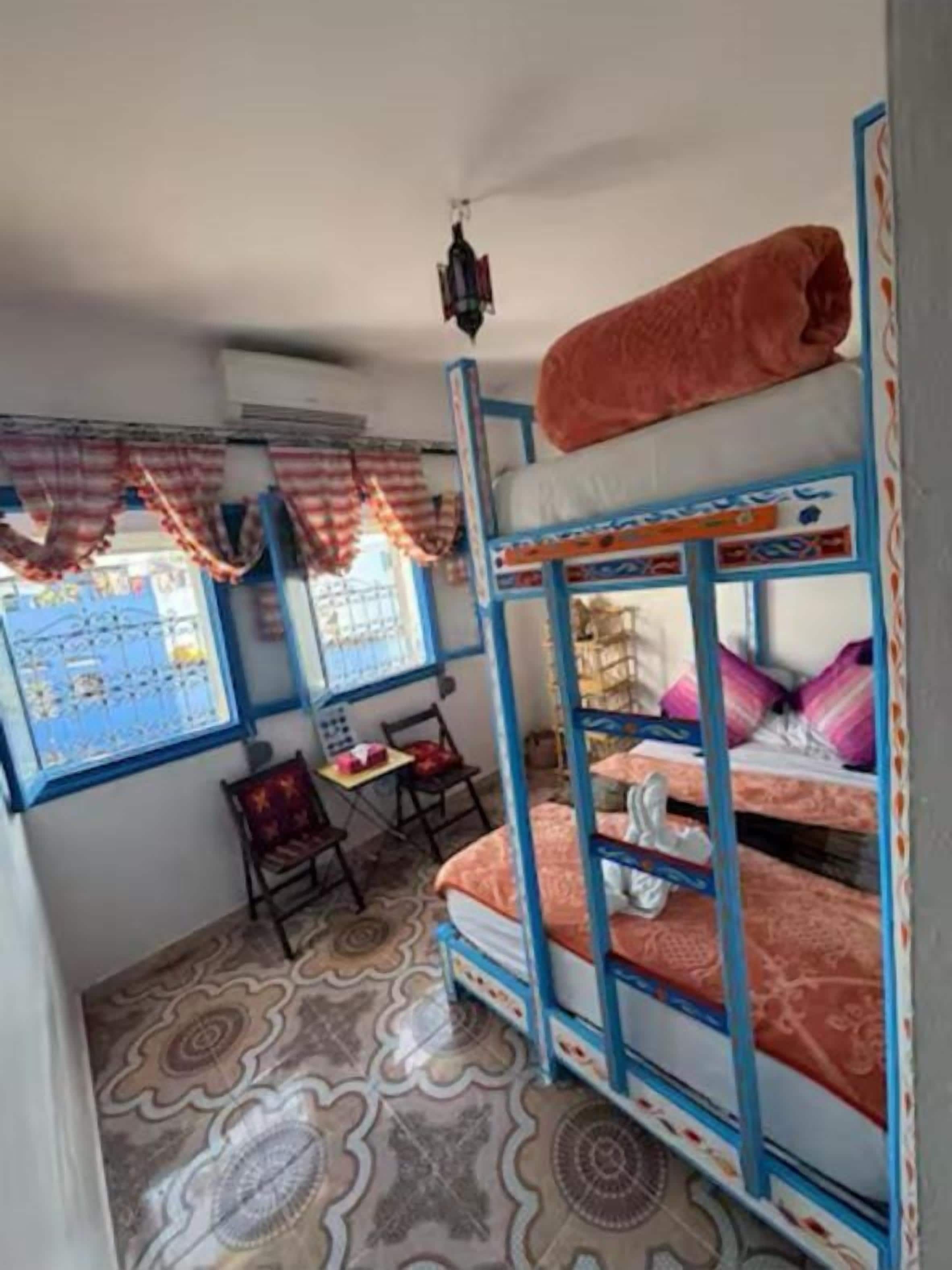 Une chambre avec des lits superposés, un bureau et une chaise.