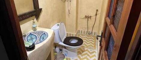 A small bathroom with a toilet, sink, and mirror.