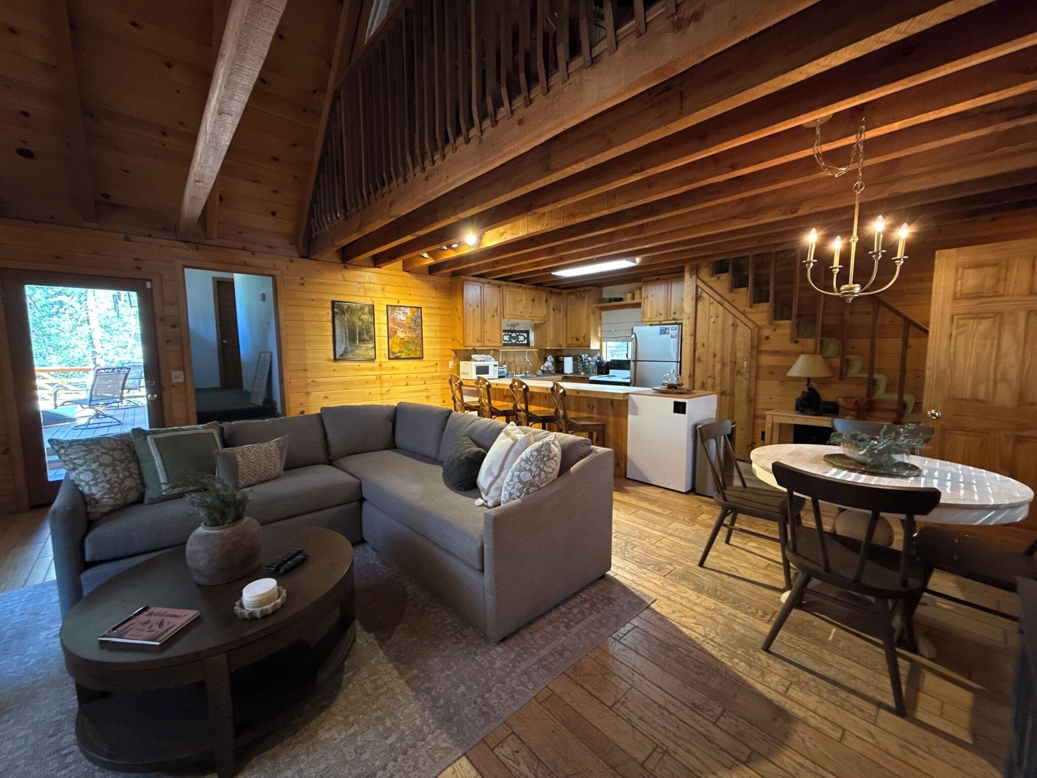 Acogedor interior de cabaña con un sofá seccional, una mesa de comedor y una zona de cocina.
