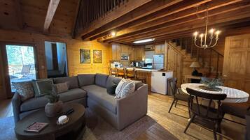 Acogedor interior de cabaña con un sofá seccional, una mesa de comedor y una zona de cocina.