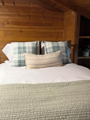 A bed with plaid pillows and a textured throw blanket.