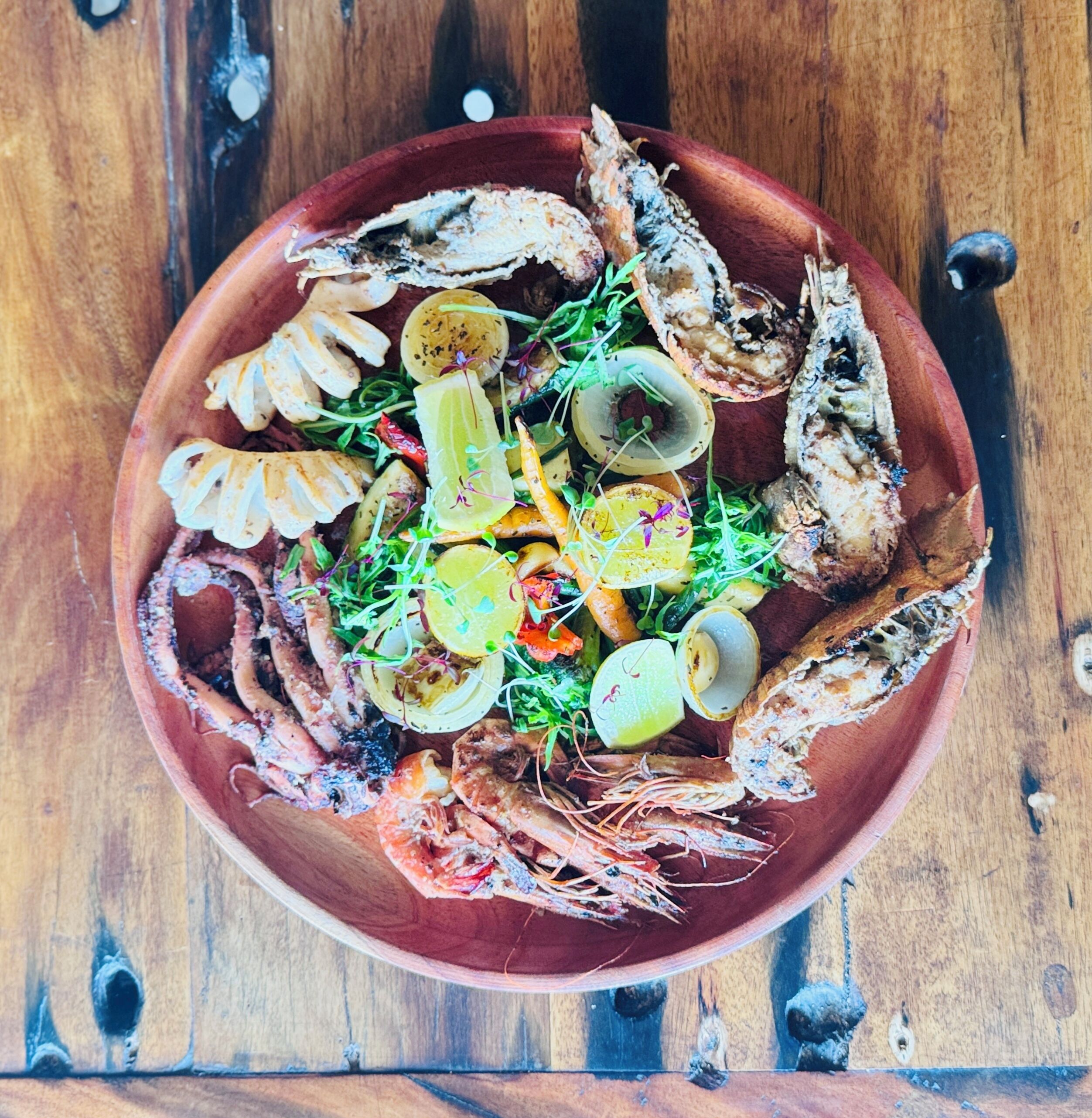 Una mesa de madera con diversos mariscos y verduras.