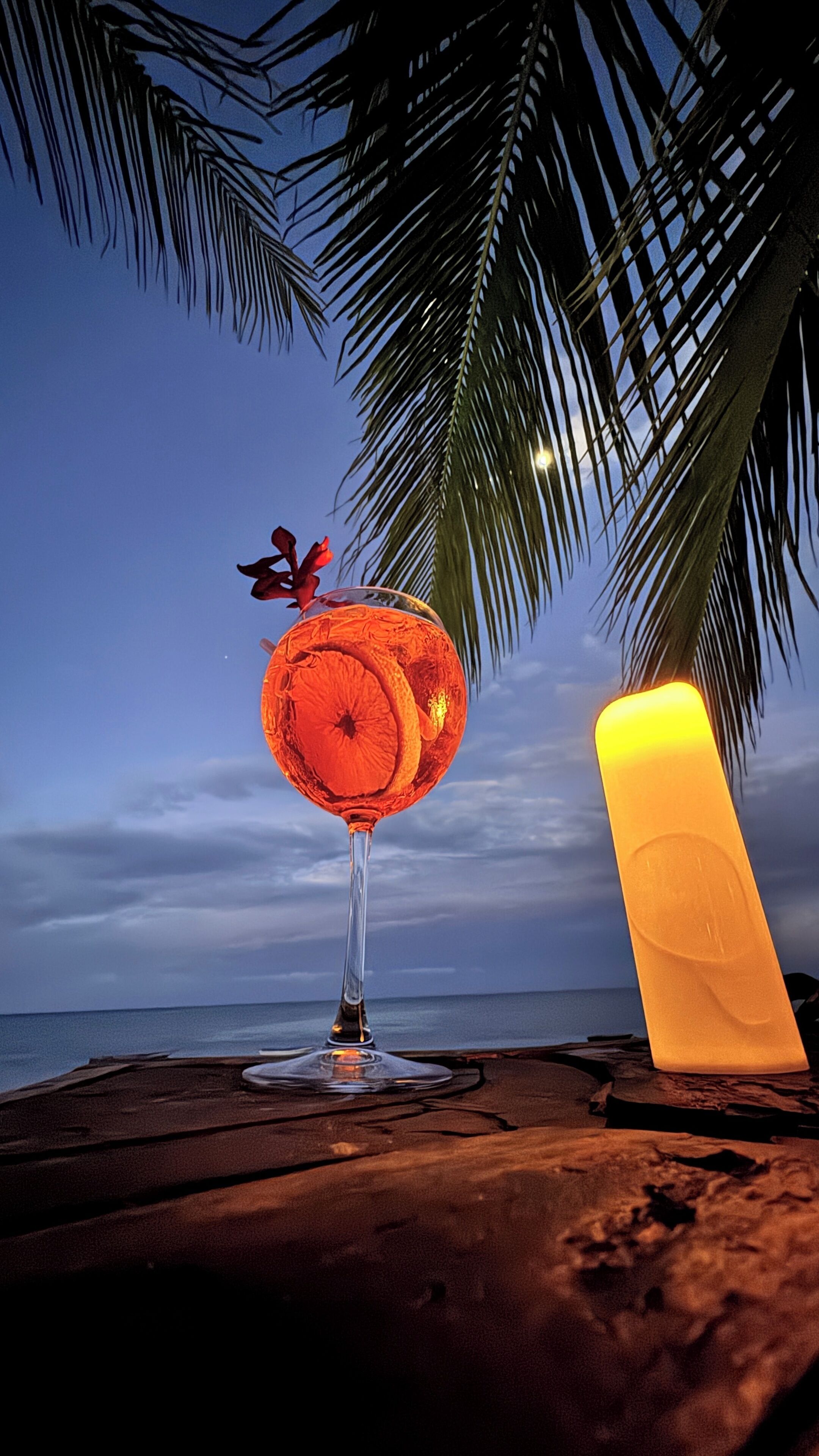 Een strandscène met een cocktailglas, een kaars en een palmboom.