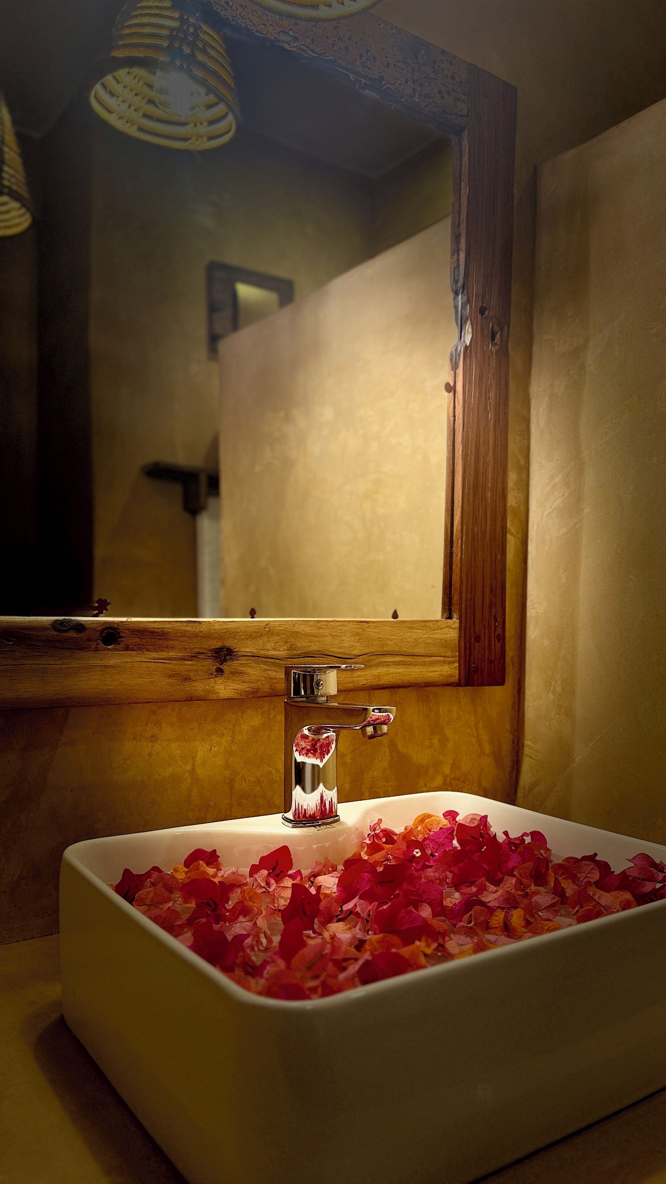 A bathroom with a rectangular sink, a mirror, and a wooden frame.
