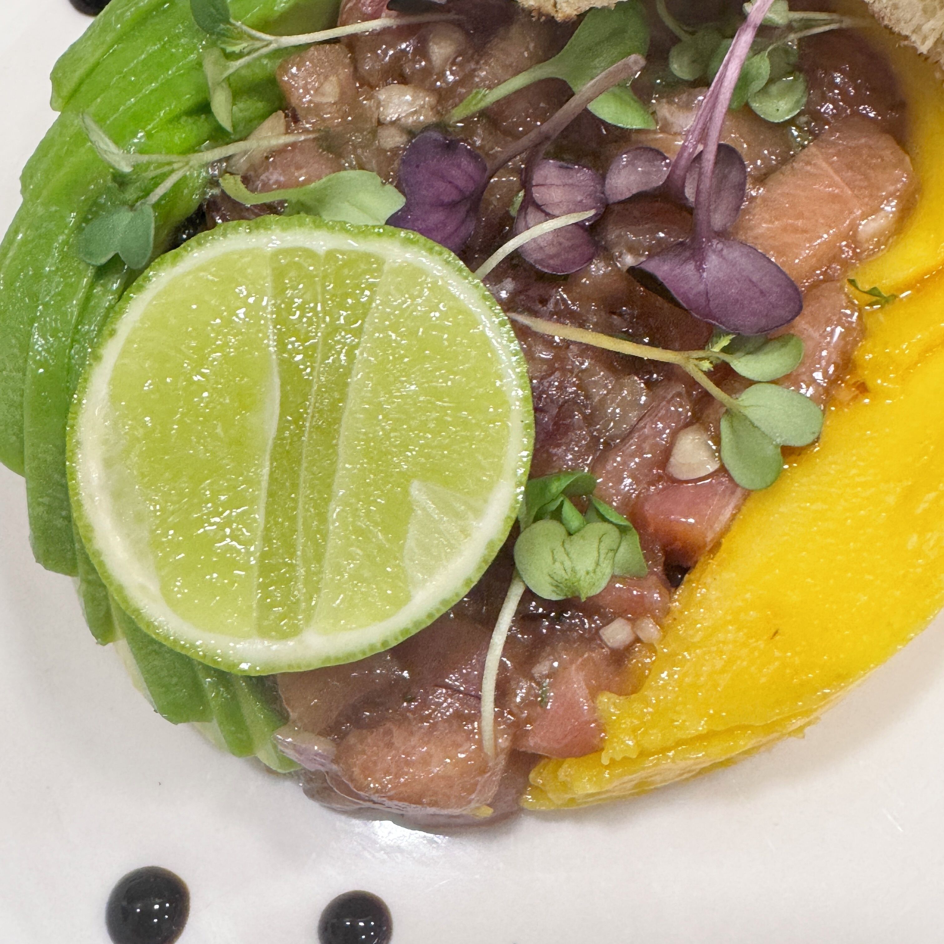 A plate with a slice of lime, meat, and greens.