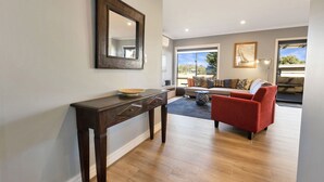 Una sala moderna con un aparador de madera, un sillón rojo y un sofá con cojines estampados.