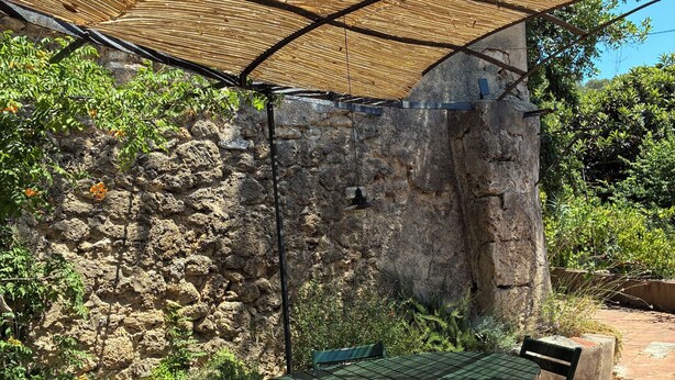 A patio with a table and chairs, a woven canopy, and a stone wall. - La petite maison du Couvent des Ecrevisses, sleeps 4 in the heart of Barjols (Barjols)