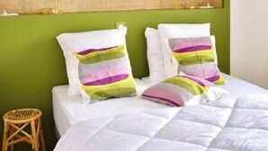 A bed with white bedding and colorful pillows, a green headboard, and a small wooden stool. - La petite maison du Couvent des Ecrevisses, sleeps 4 in the heart of Barjols (Barjols)