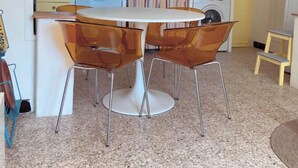 A compact kitchen with yellow cabinets, a round table with two chairs, and a washing machine. - La petite maison du Couvent des Ecrevisses, sleeps 4 in the heart of Barjols (Barjols)