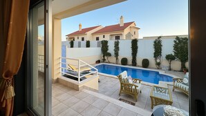 Un balcón con piscina, mobiliario exterior y vistas a un edificio de tejado rojo.
