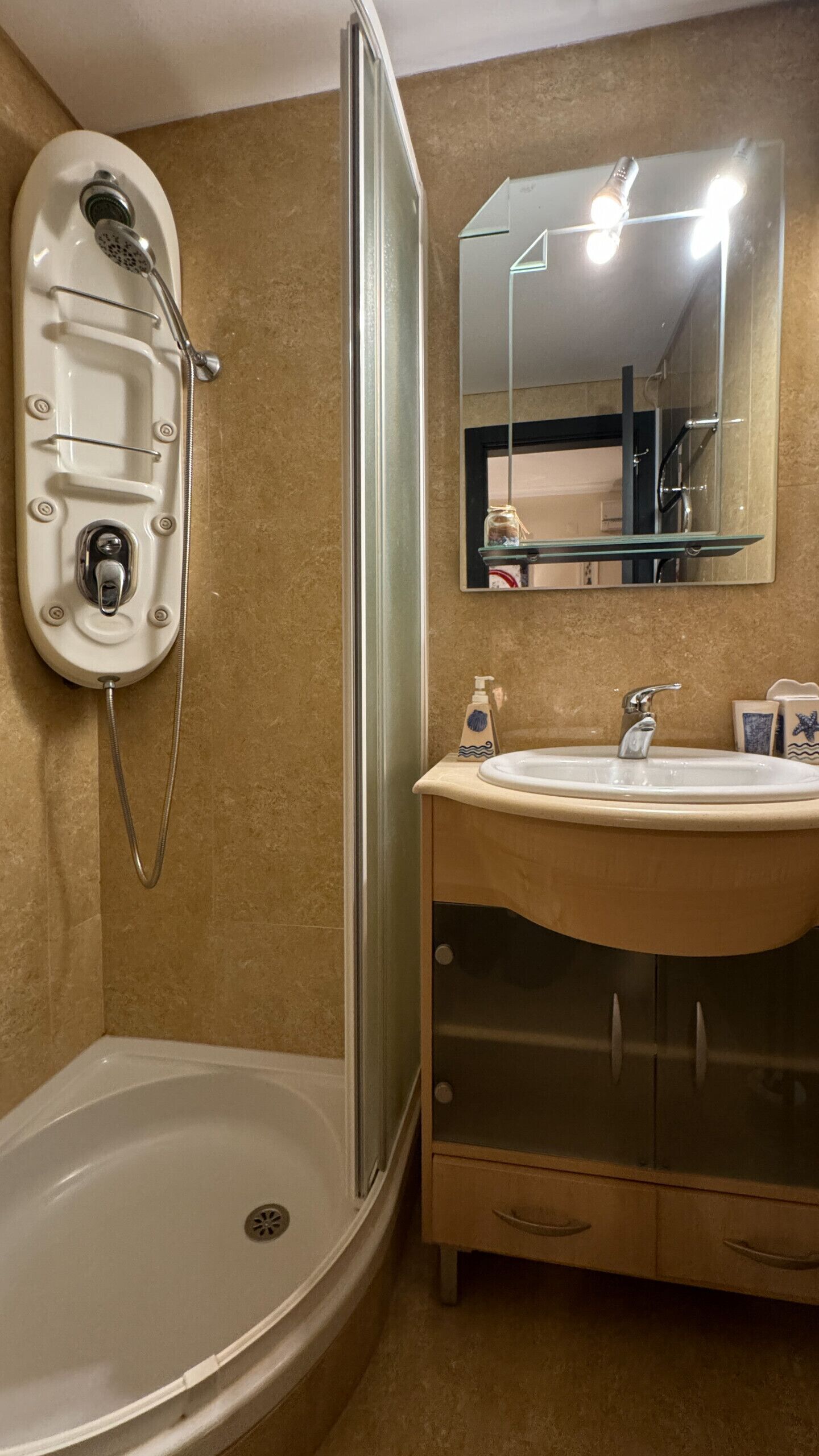 A bathroom with a shower, a sink, a mirror, and a vanity cabinet.